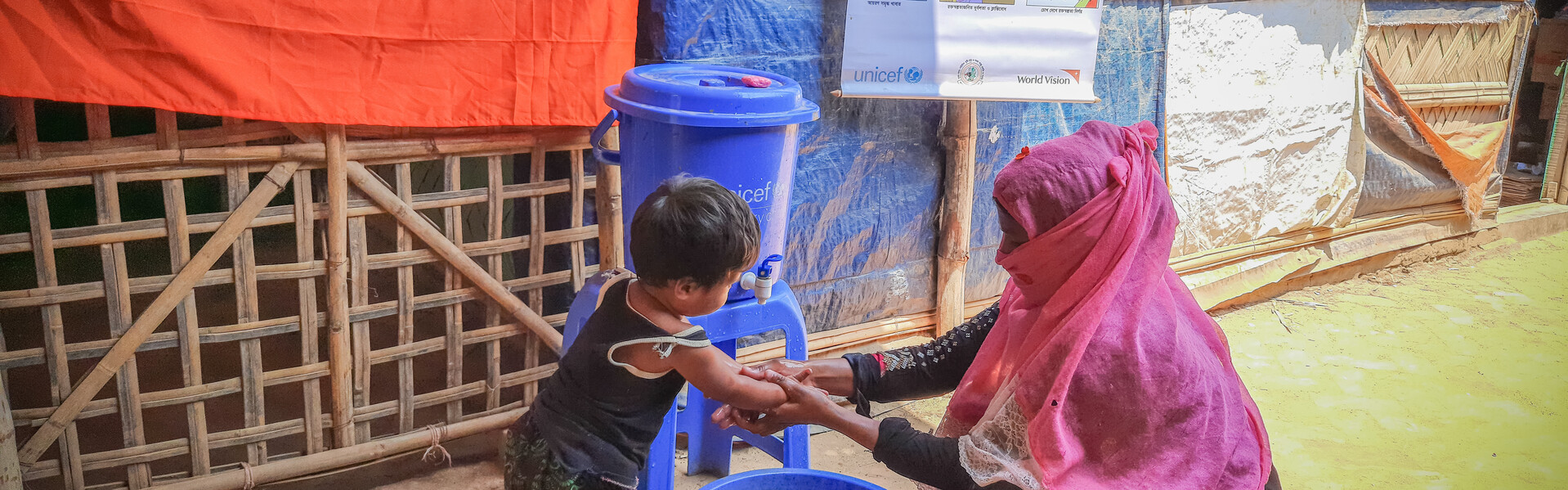 Corona-Prävention Bangladesch: Eine Helferin zeigt einem Jungen, wie richtiges Händewaschen geht