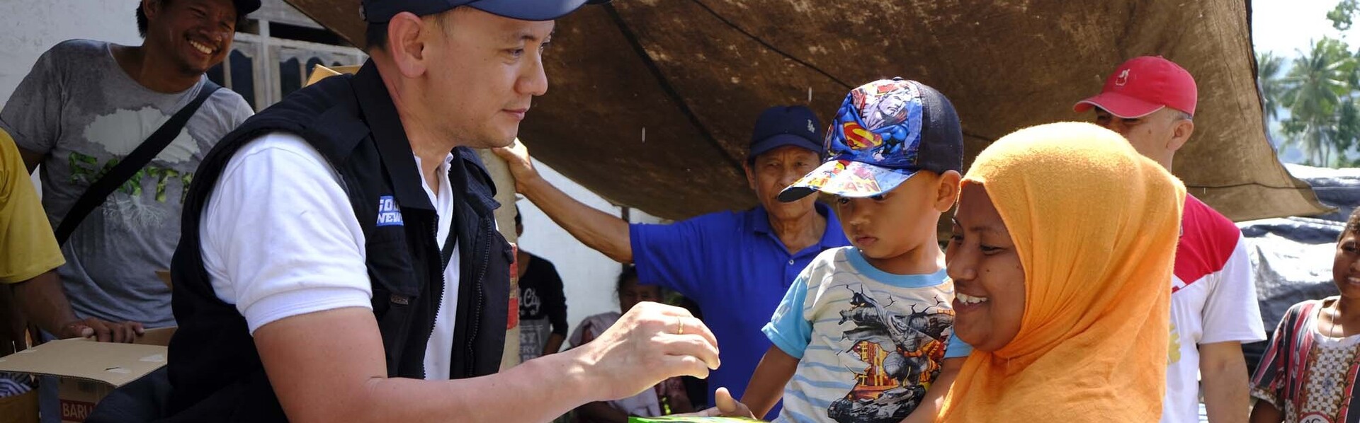 Nach einer Naturkatastrophe in Indonesien verteilt ein Helfer Hilfsgüter an Menschen 