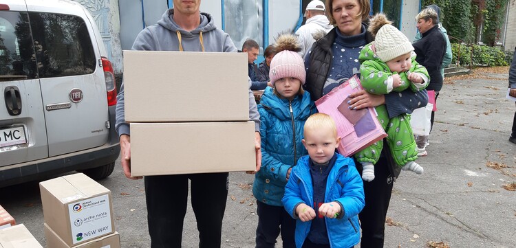 Eine Familie aus der Ukraine hält Pakete mit Hilfsgütern in den Händen