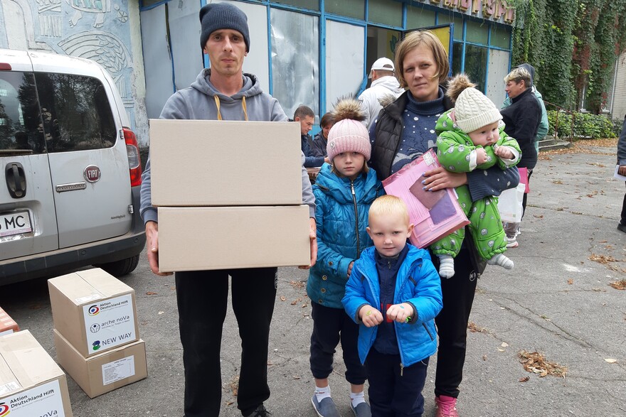 Eine Familie aus der Ukraine hält Pakete mit Hilfsgütern in den Händen