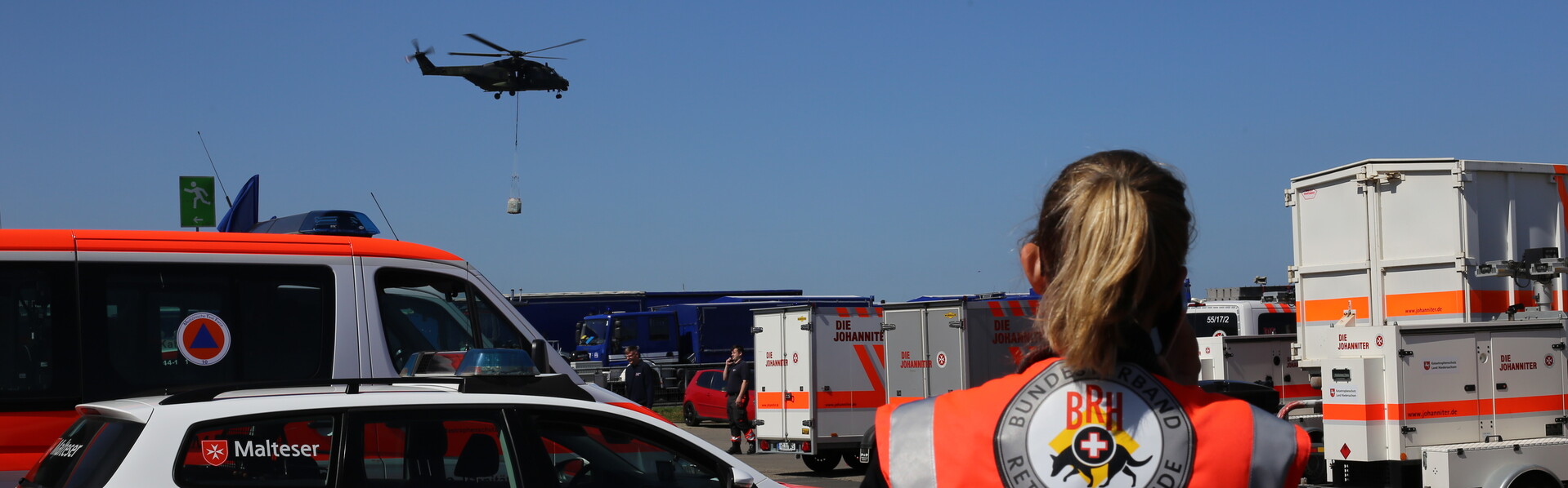 Eine Helferin beobachtet dein Einsatz eines Rettungshubschraubers