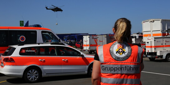 Eine Helferin beobachtet dein Einsatz eines Rettungshubschraubers