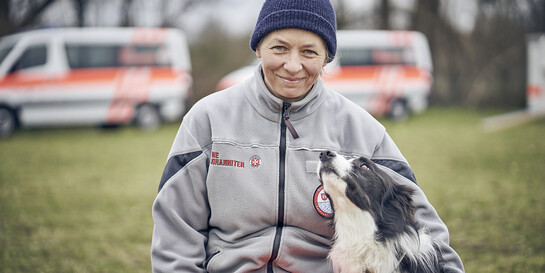 Helferin der Johanniter mit einem Hund im Flutgebiet