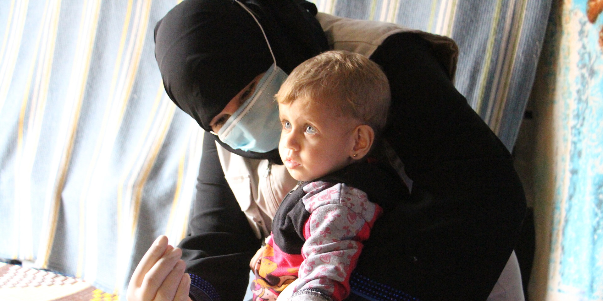Das syrische Mädchen Ruqayya wird von einer Helferin betreut 
