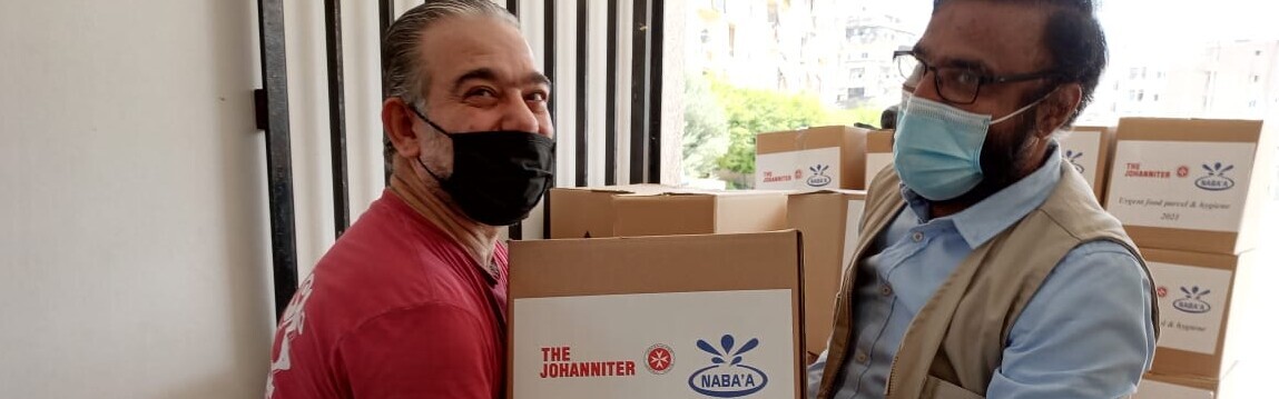 Ein Helfer der Johanniter-Partnerorganisation Nabaa übergibt ein Hilfspaket für Menschen im Libanon