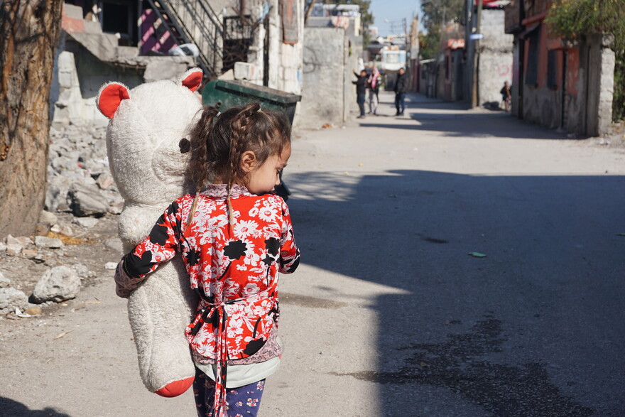 Ein Mädchen trägt nach dem Erdbeben in der Türkei einen großen Teddybär auf dem Arm