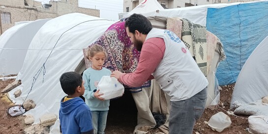 Ein Helfer von einer Partnerorganisation der Johanniter verteilt Lebensmittel an obdachlose Kinder im Erdbebengebiet Türkei-Syrien