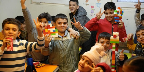 Eine Gruppe von Kindern spielt mit bunten Legosteinen, Help – Hilfe zur Selbsthilfe