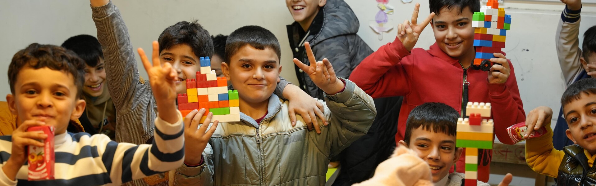 Eine Gruppe von Kindern spielt mit bunten Legosteinen, Help – Hilfe zur Selbsthilfe
