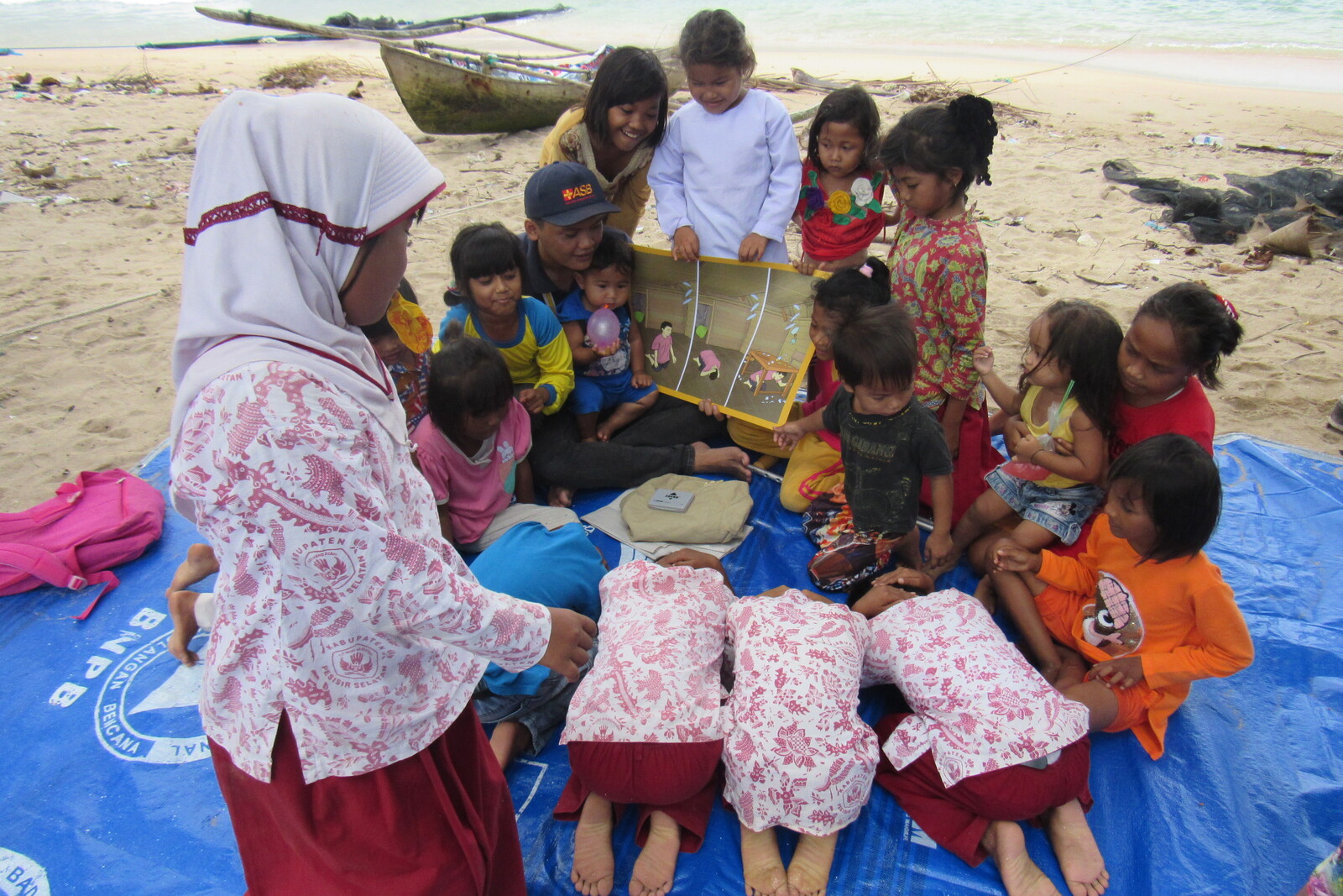 Mädchen und Jungen in Indonesien üben an einem Strand richtiges Verhalten bei Naturkatastrophen