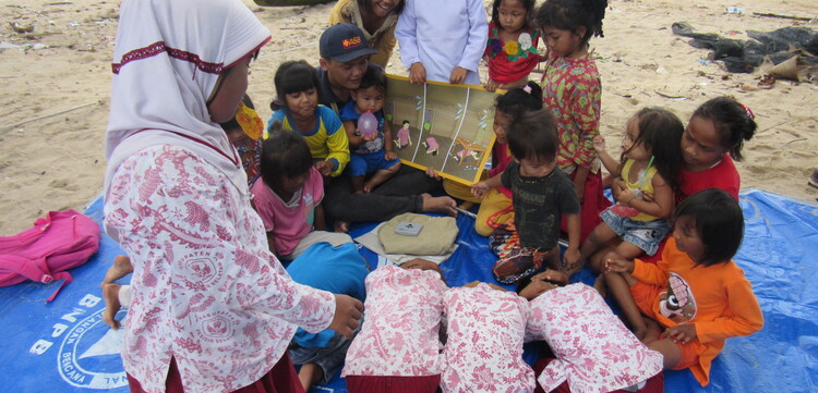 Mädchen und Jungen in Indonesien üben an einem Strand richtiges Verhalten bei Naturkatastrophen