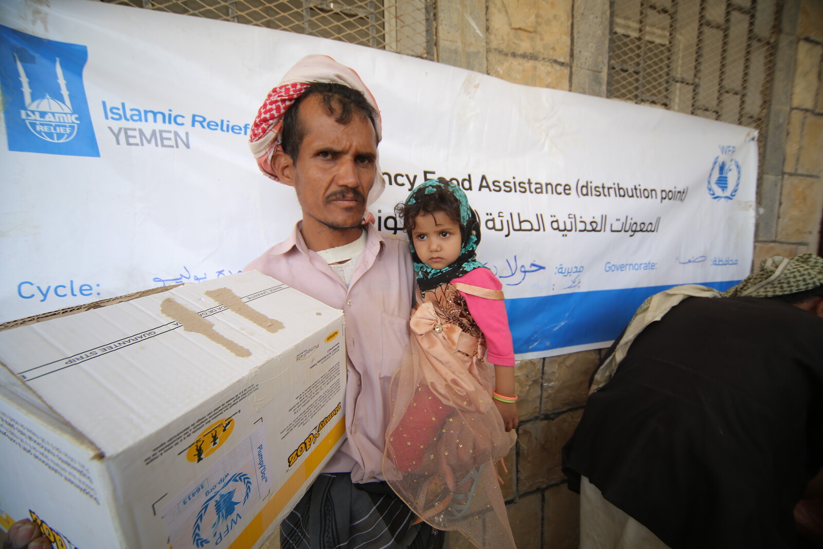Im Jemen nehmen ein Mann und seine Tochter ein Paket mit rettender Nothilfe entgegen