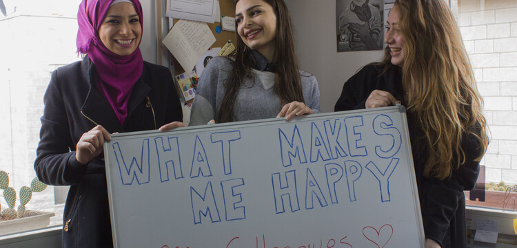 Frauen halten ein Schild in Jordanien hoch mit der Aufschrift "#whatmakesmehappy"