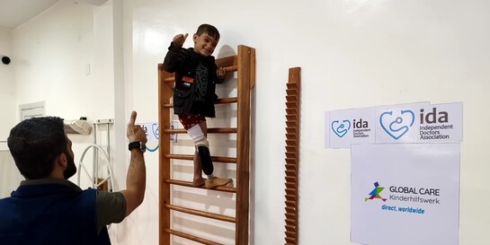 Ein Junge und ein Helfer bei einer physiotherapeutischen Behandlung