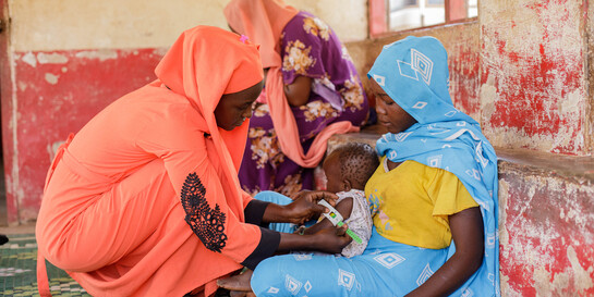 Zwei Frauen im Südsudan messen den Umfang eines Arms bei einem Kind