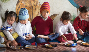Kinder sitzen auf dem Boden und essen