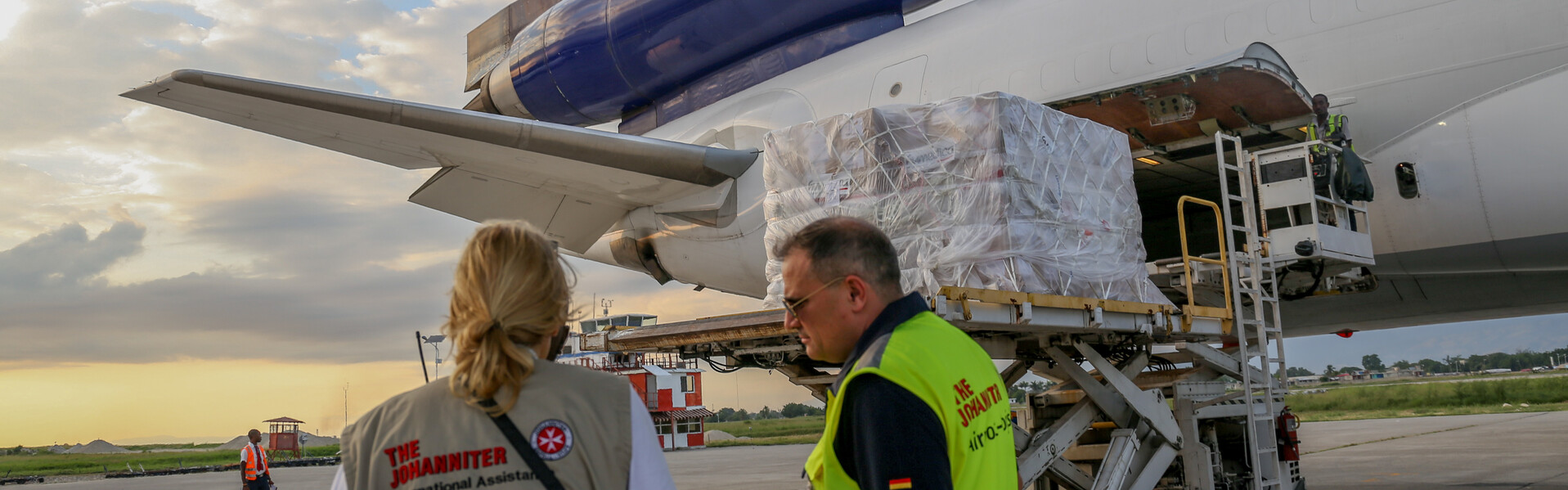 Helfer stehen bei einem Hilfsflieger mit Hilfsgütern für Haiti.