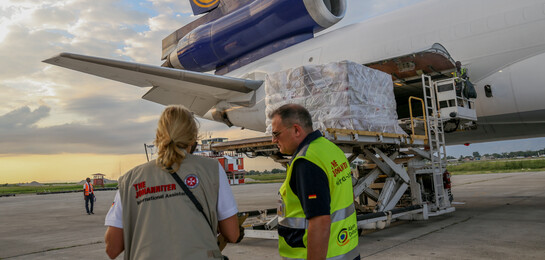 Helfer stehen bei einem Hilfsflieger mit Hilfsgütern für Haiti.