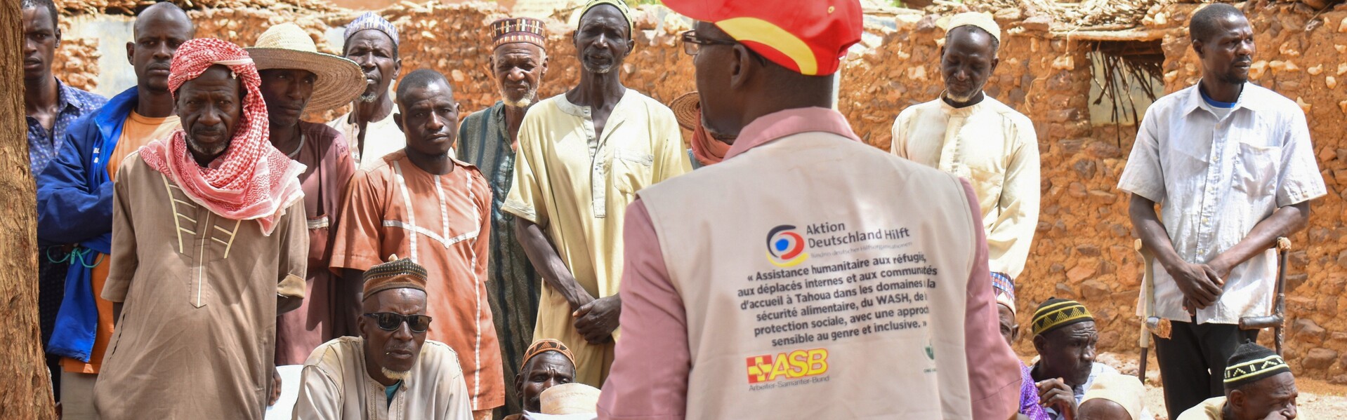 Ein Helfer von ASB steht im Niger vor einer Menschengruppe