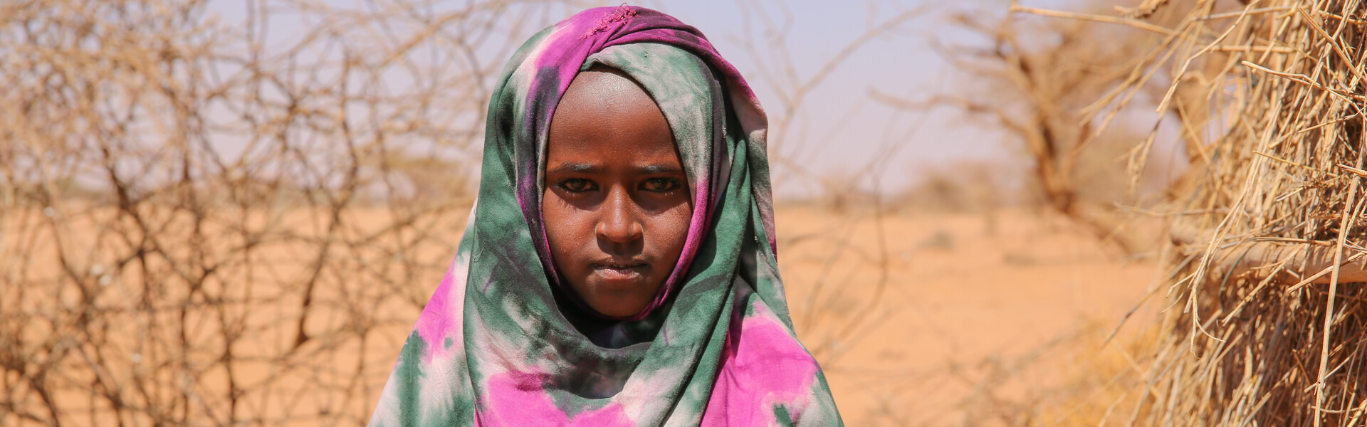 Kind in Somalia hält trockenes Stroh in den Händen.