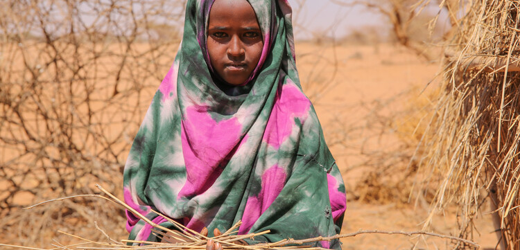 Kind in Somalia hält trockenes Stroh in den Händen.