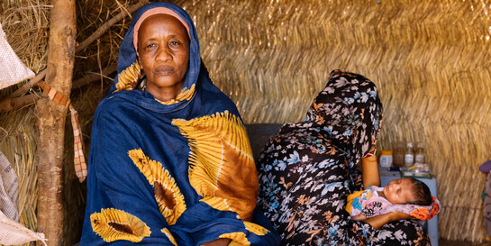 Eine Frau im Südsudan sitzt bei einer Mutter und ihrem Baby