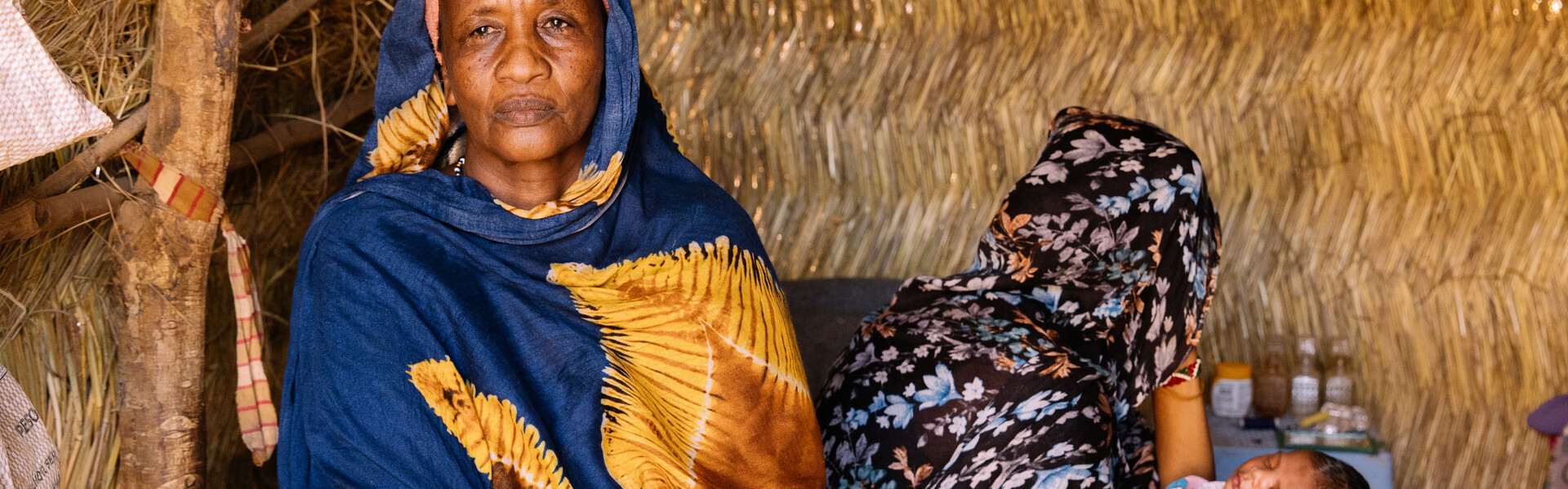 Eine Frau im Südsudan sitzt bei einer Mutter und ihrem Baby