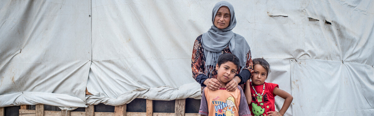 Eine aus Syrien geflüchtete Familie steht vor ihrer Notunterkunft 