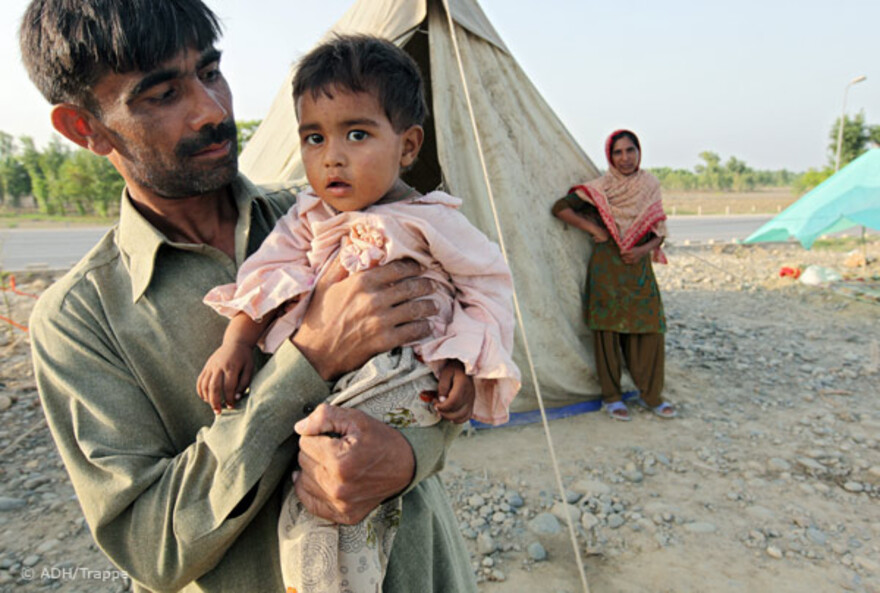 2010.08.27-vater-kind-an-autobahn Flut Pakistan:27.08.2010, Pakistan, Nowshera - Hochwasser Pakistan. Auf der Autobahnstrecke Richtung Peshawar campieren Flüchtlinge des Hochwassers in Zelten.