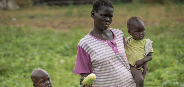 Mutter trägt ihr Kind im Südsudan über das Gurkenfeld