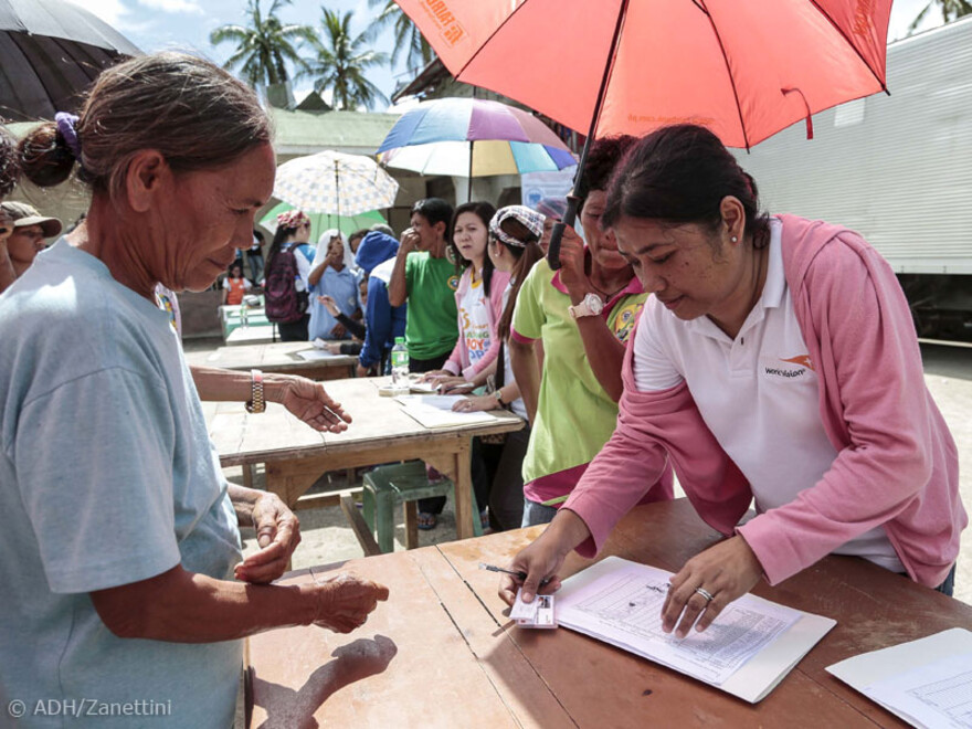 Vor Tischen stehen die Menschen in Tabogon an und lassen sich registrieren