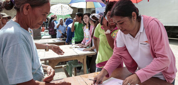 Vor Tischen stehen die Menschen in Tabogon an und lassen sich registrieren