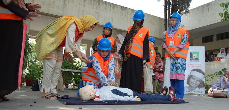 Frauen in Pakistan über an einer Puppe die Herzmassage Frauen in Pakistan über an einer Puppe die Herzmassage