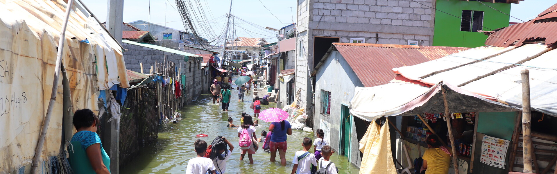 Menschen auf den Philippinen waten durch eine überschwemmte Seitenstraße