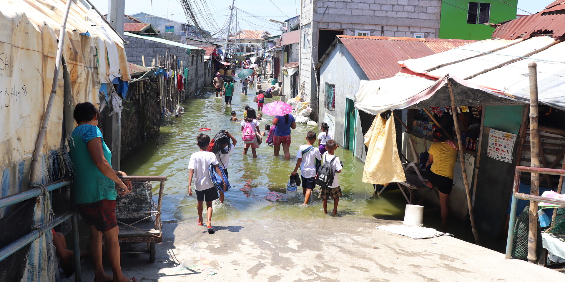 Menschen auf den Philippinen waten durch eine überschwemmte Seitenstraße