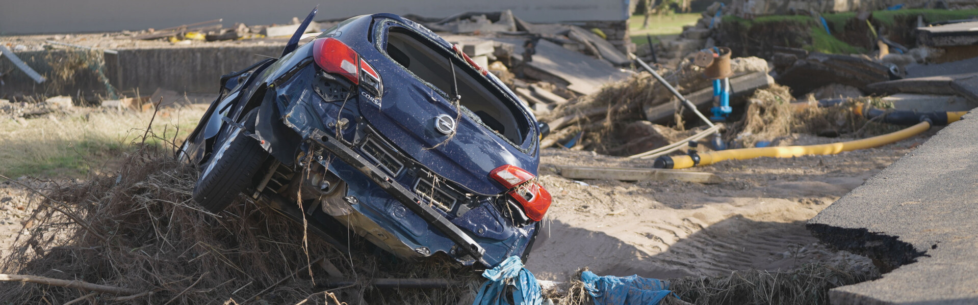 Ein beschädigtes Auto und eine zerstörte Straße nach der Flut