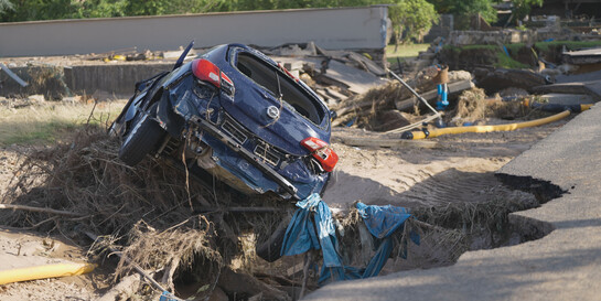 Ein beschädigtes Auto und eine zerstörte Straße nach der Flut