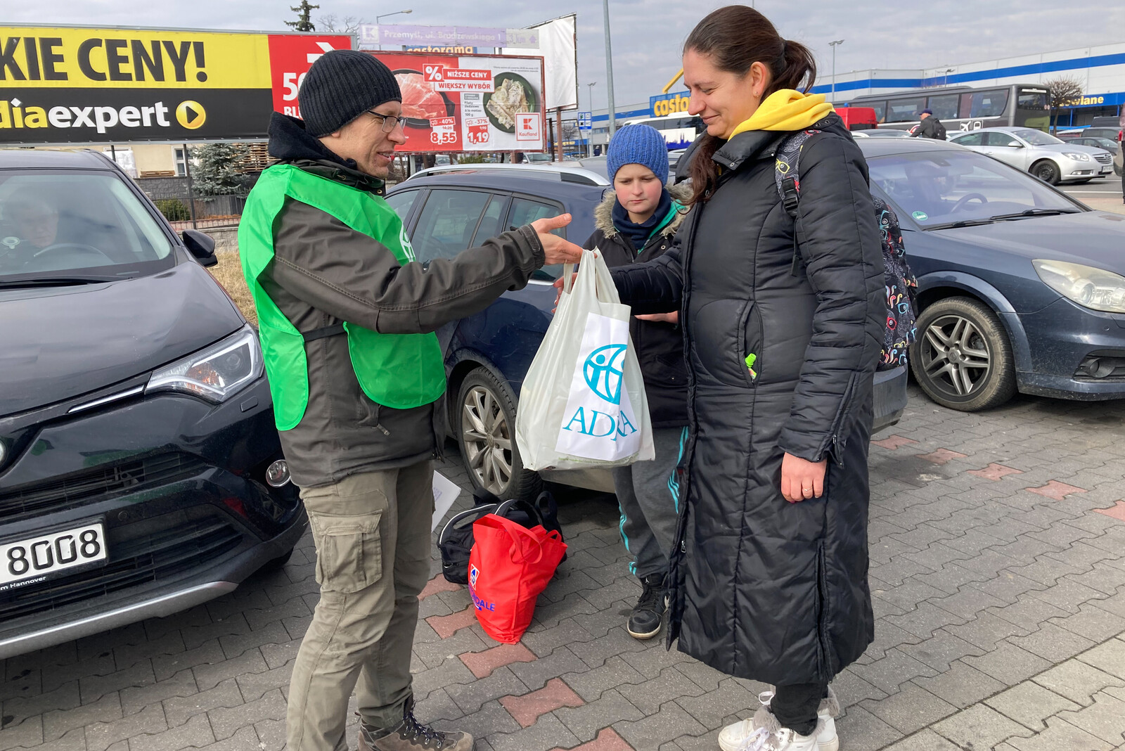 Ein Helfer von ADRA überreicht einer Frau eine Tüte mit Hilfsgütern