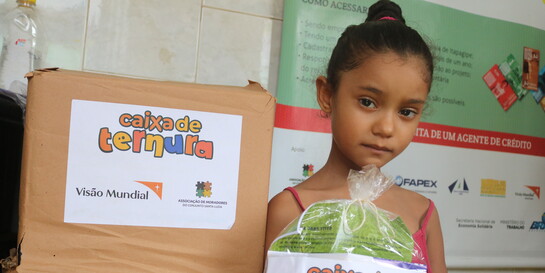 Ein Mädchen in Brasilien hält eine Tüte mit einer Lieferung von der Hilfsorganisation World Vision in der Hand