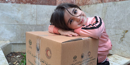Ein Mädchen in Syrien freut sich über ein Hilfspaket
