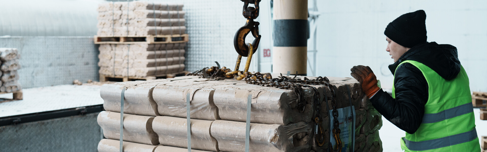 Johanniter leisten Winterhilfe in der Ukraine Ein Mann mit gelber Sicherheitsweste steht neben einer mit Holzbriketts beladenen Palette