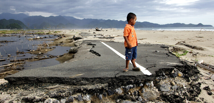 Auf einer vom Tsunami zerstörten Straße auf der indonesischen Insel Sumatra steht ein Junge Auf einer vom Tsunami zerstörten Straße auf der indonesischen Insel Sumatra steht ein Junge