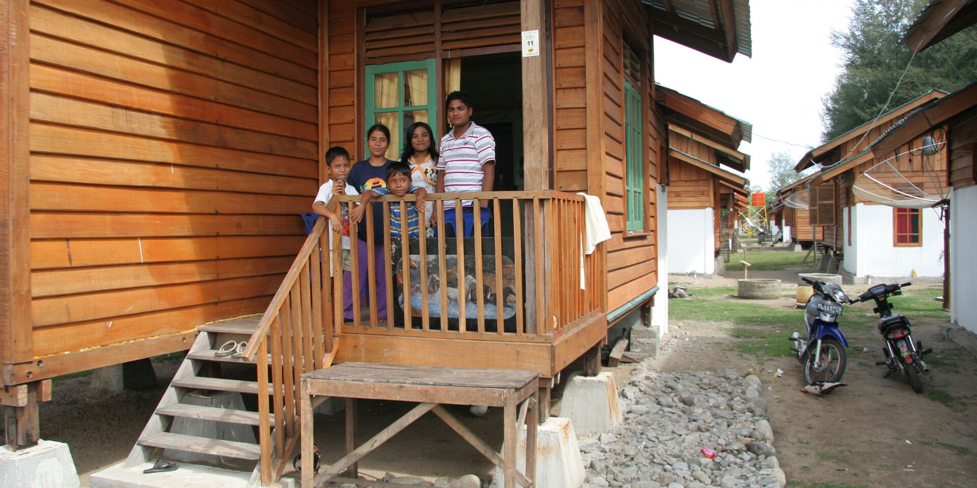 Eine Familie in Indonesien auf der Veranda ihres wiederaufgebauten Hauses