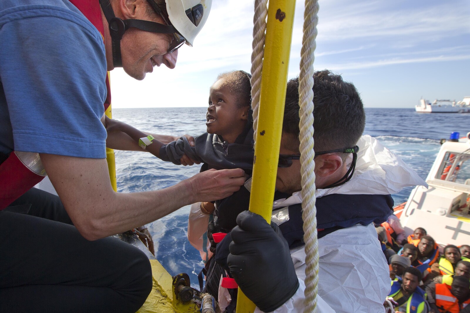 Helfer der SOS Mediterranee retten ein junges Kind aus einem Flüchtlingsboot auf dem Mittelmeer.