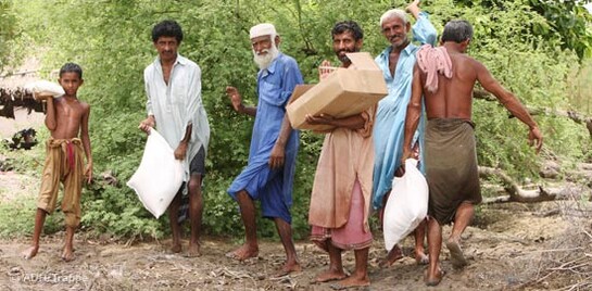 Flut Pakistan: Männer mit Hilfsgütern