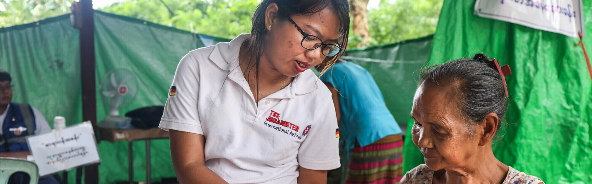 Eine Ärztin der Johanniter versorgt in Myanmar eine ältere Frau mit Medikamenten