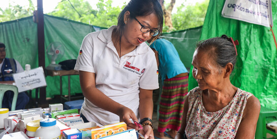 Eine Ärztin der Johanniter versorgt in Myanmar eine ältere Frau mit Medikamenten