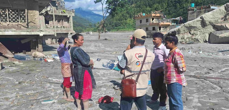 Ein humanitärer Helfer unterhält sich zwischen den Trümmern der Sturzflut in Nepal mit betroffenen Personen