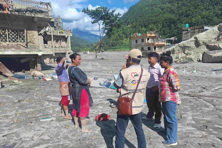 Ein humanitärer Helfer unterhält sich zwischen den Trümmern der Sturzflut in Nepal mit betroffenen Personen