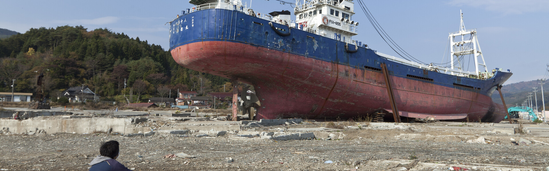Ein Mann blickt auf ein gestrandetes Schiff nach dem schweren Erdbeben und Tsunami in Japan
